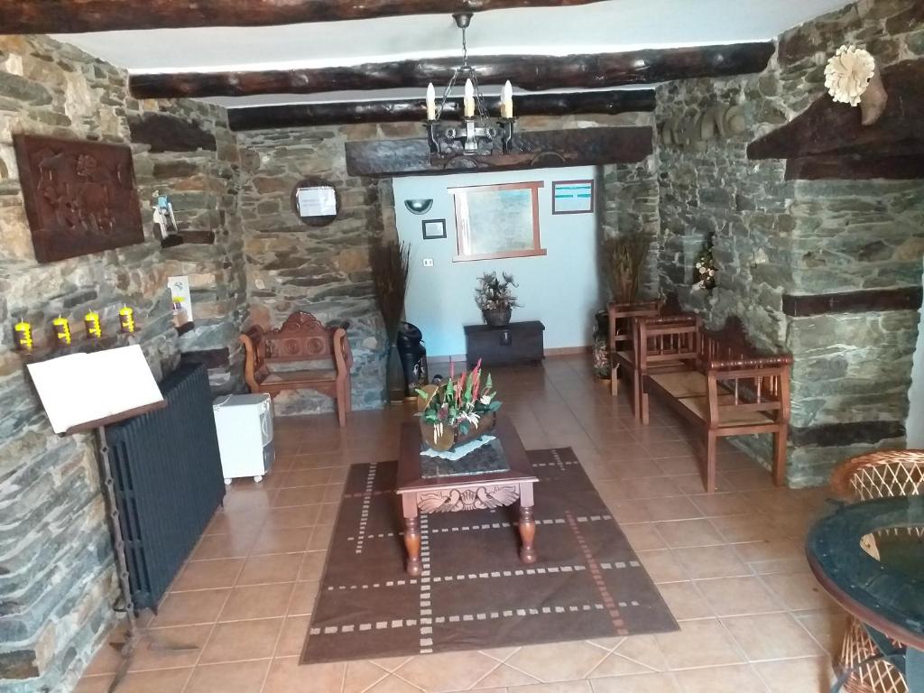 ein Wohnzimmer mit Steinwänden sowie einem Tisch und Stühlen in der Unterkunft Casa Quiroga in Lamas