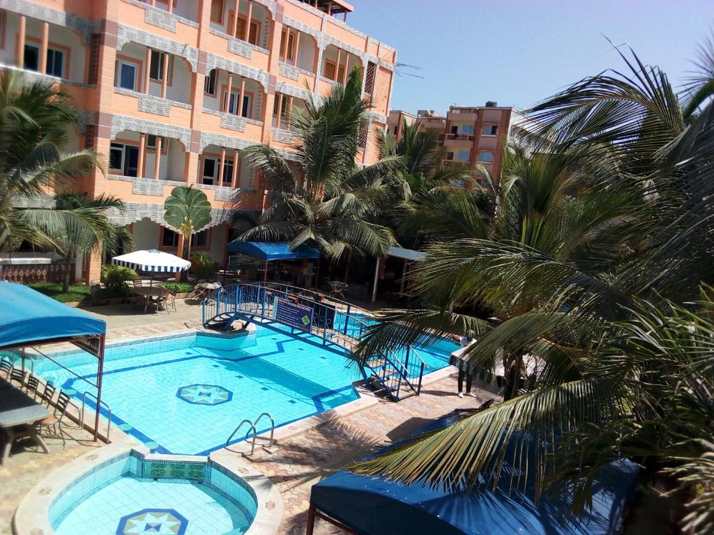 a large swimming pool with palm trees and a building at Premier Guest Residence Hotel in Malindi