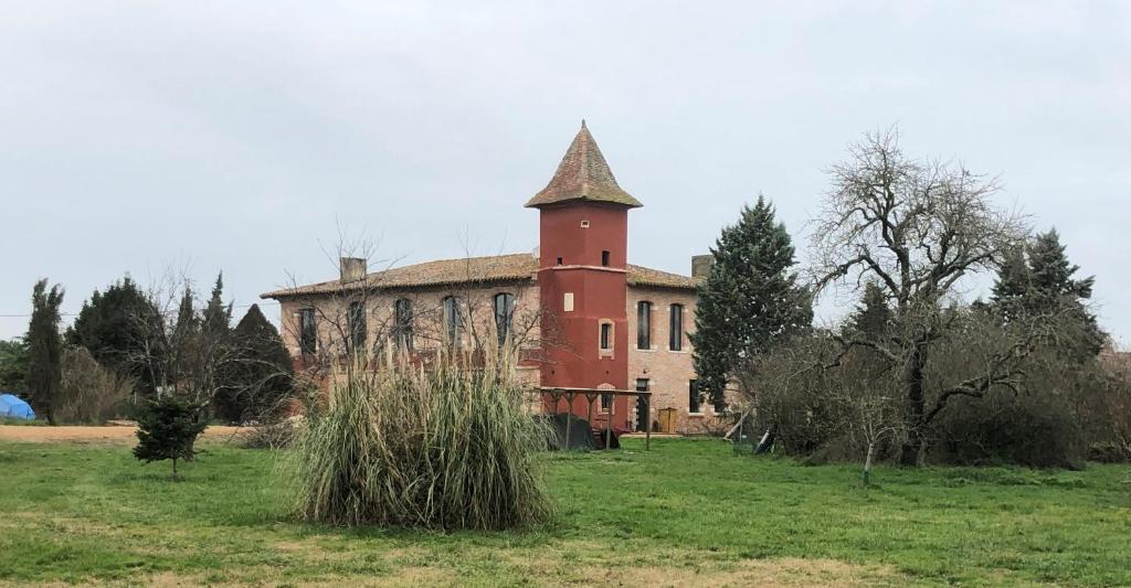 un antiguo edificio de ladrillo con una torre en un campo en chateau fourclins, en Merville