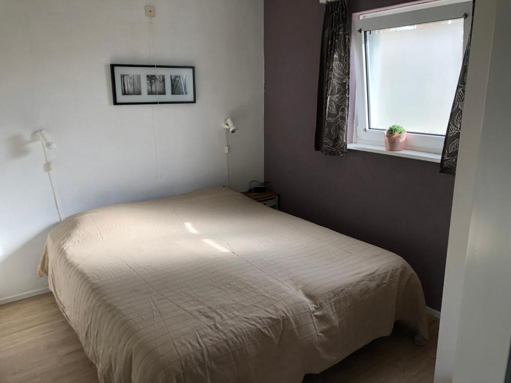a small bedroom with a bed and a window at Hello Zeeland - vakantiewoning Porrenaerstraat 2 in Aagtekerke