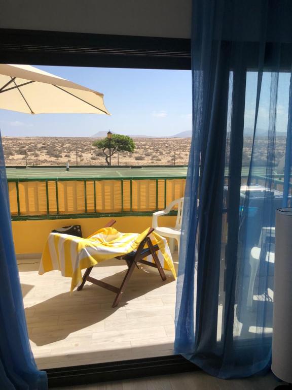 einen Balkon mit einem Tisch und einem Sonnenschirm in der Unterkunft Dunasol in Corralejo