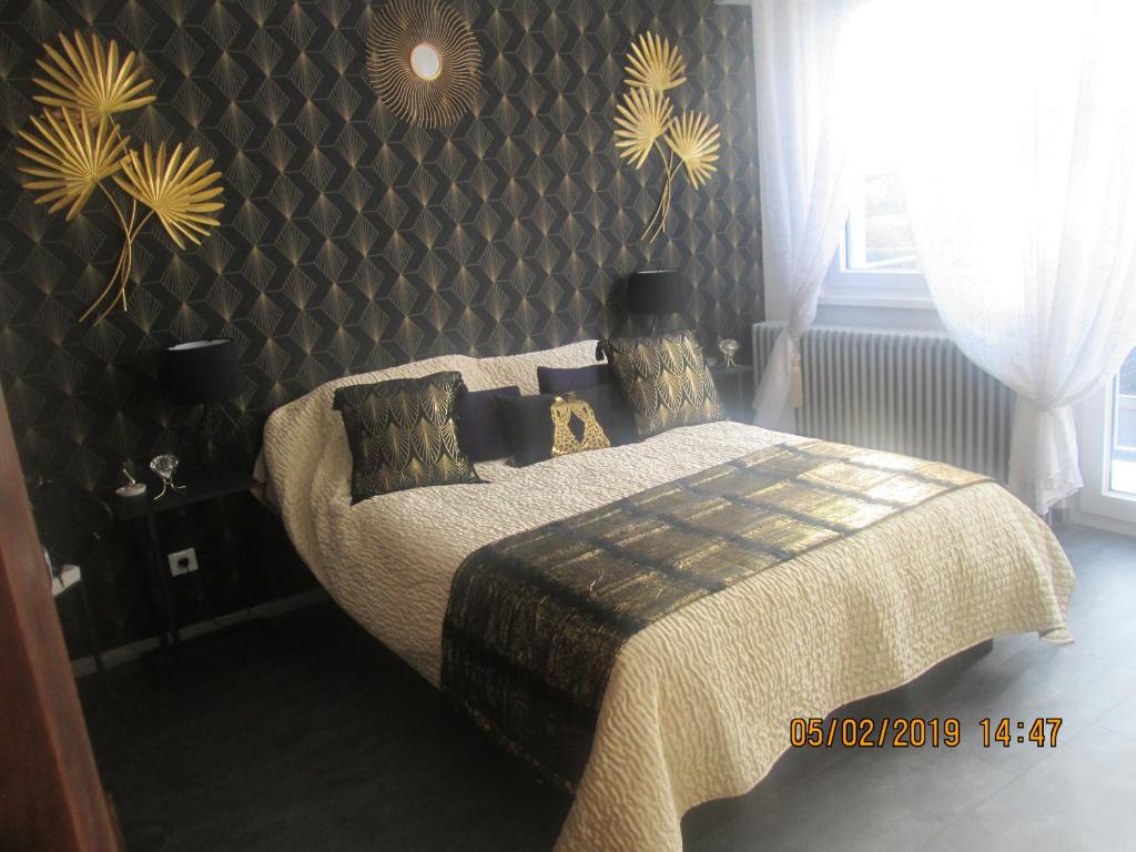 a bedroom with a bed with a blanket and a wall at Gîte du Coq in Lingolsheim