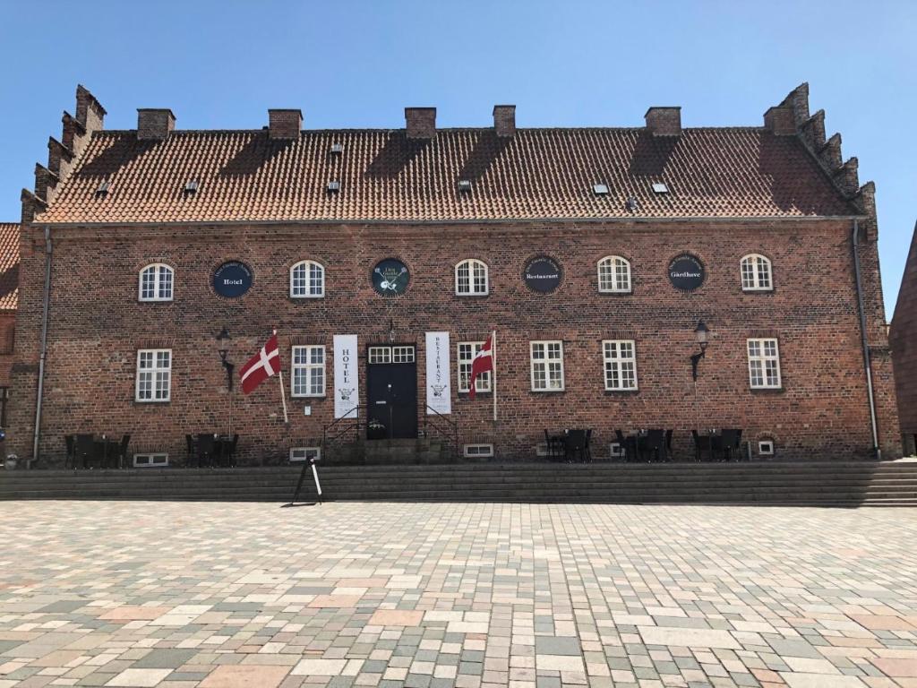 un gran edificio de ladrillo rojo con banderas delante en Den Gamle Arrest, en Ribe