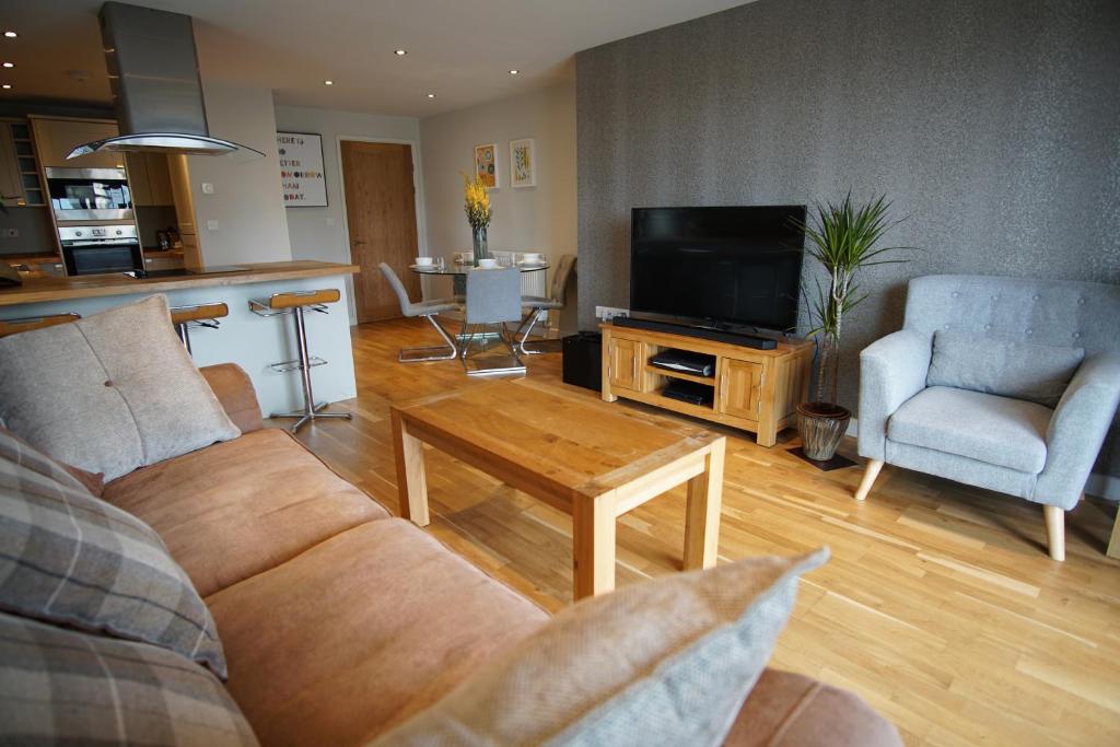 a living room with a couch and a table and a tv at Ocean Views 3 in Newquay