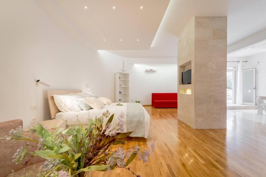 een witte slaapkamer met een bed en een bank bij Deluxe Beach Apartments Renata in Split