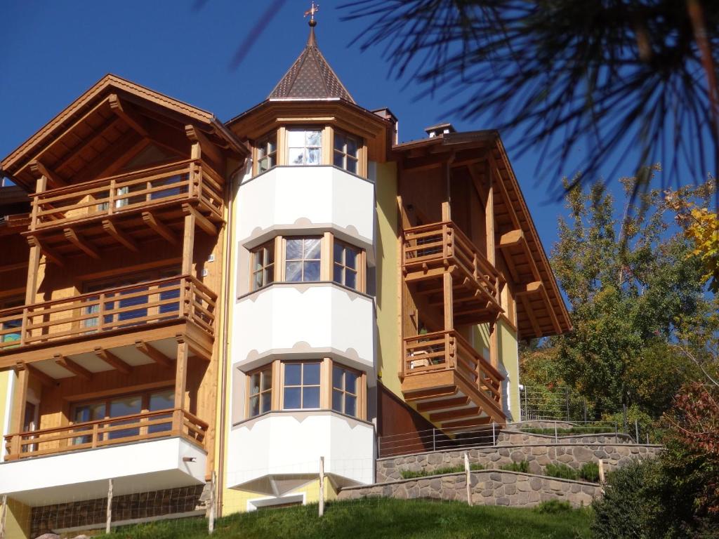 ein Apartmenthaus mit Holzbalkonen und einem Turm in der Unterkunft Chalet Residence Alpinflair in St. Ulrich in Gröden