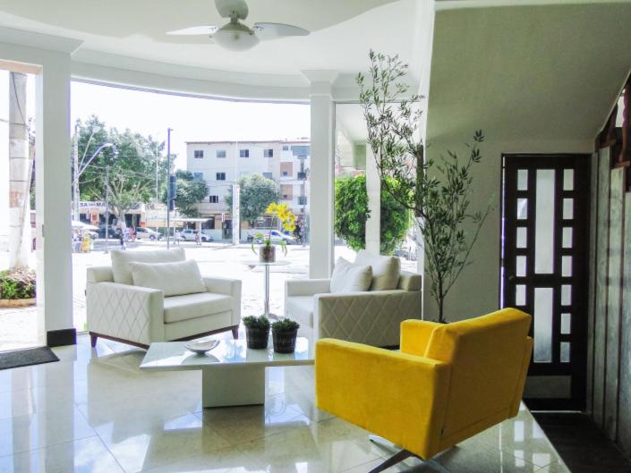 a living room with white furniture and a yellow chair at Hotel Real in Teófilo Otoni