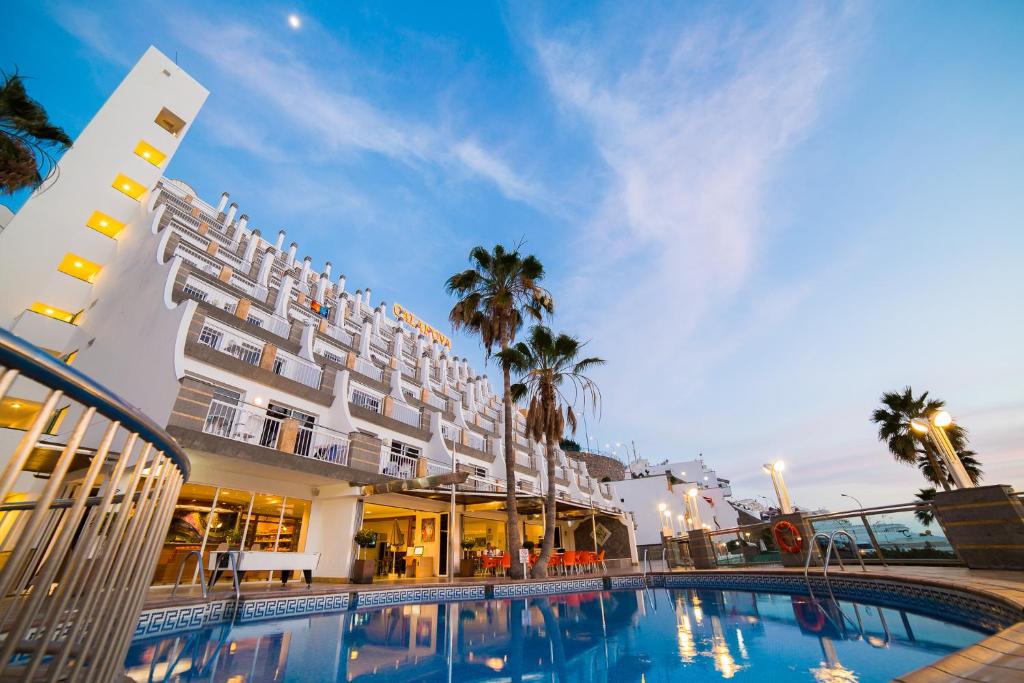 ein Hotel mit einem Pool vor einem Gebäude in der Unterkunft Cala Nova Apartamentos in Puerto Rico de Gran Canaria