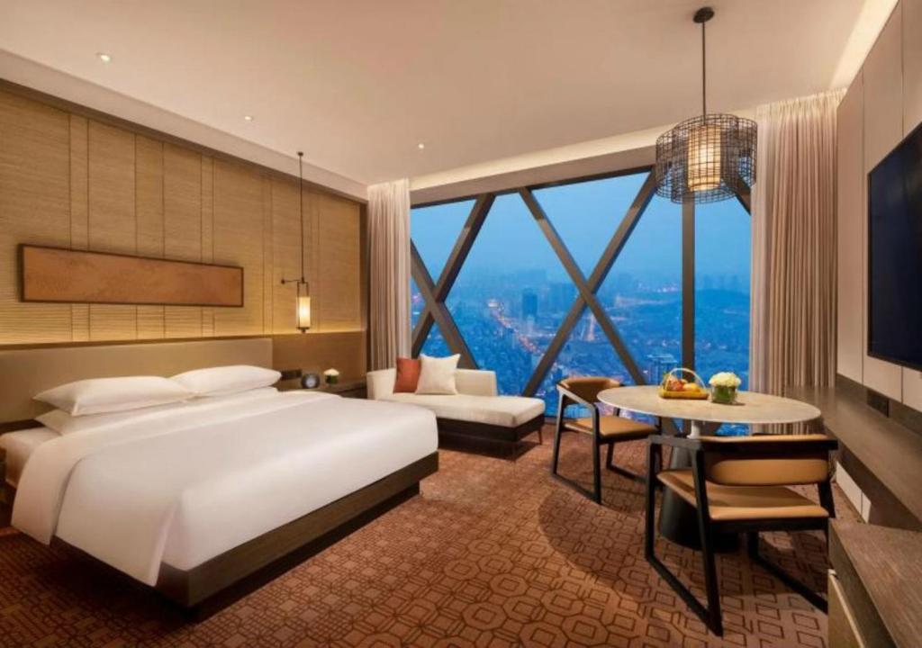 a hotel room with a bed and a large window at Hyatt Regency Zhenjiang in Zhenjiang