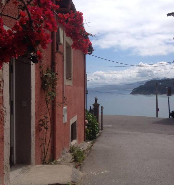 a building with red flowers on it next to a body of water at El Descanso Lastres in Colunga