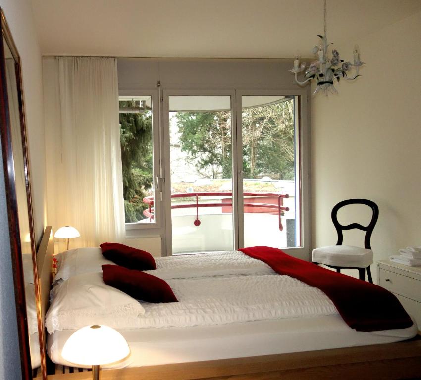 a bedroom with a bed with red pillows and a window at Exclusive Central Apartment in Basel