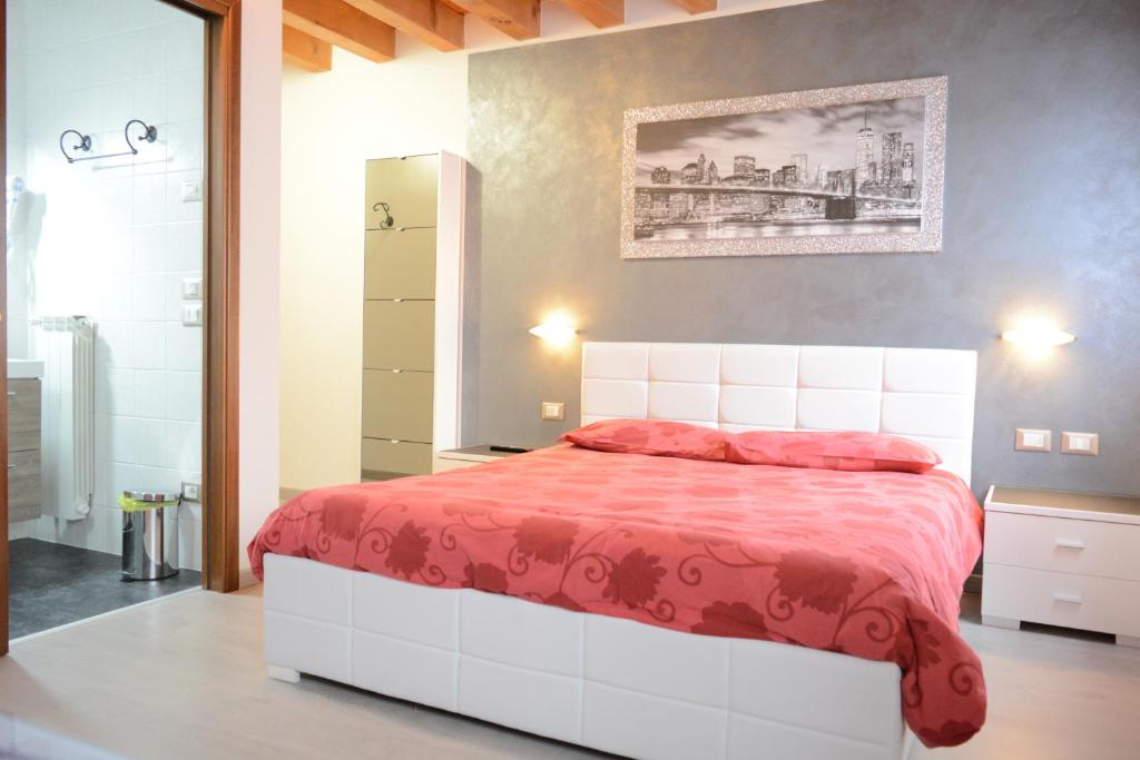 een slaapkamer met een groot bed en een rode deken bij B&B Casa Taty in Dolo