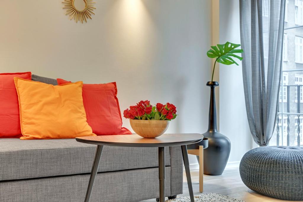 a living room with a couch and a table with flowers on it at Cooleq Apartments Ogarna by TriApart in Gdańsk