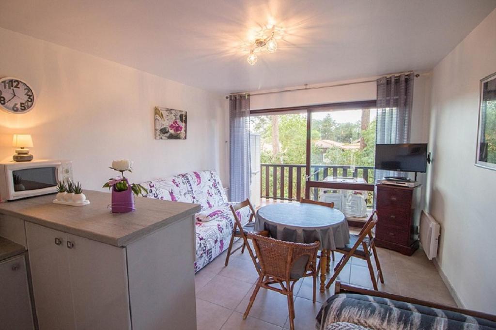 Il comprend un salon avec une table et une cuisine avec un canapé. dans l'établissement Les Genêts, à Mimizan-Plage