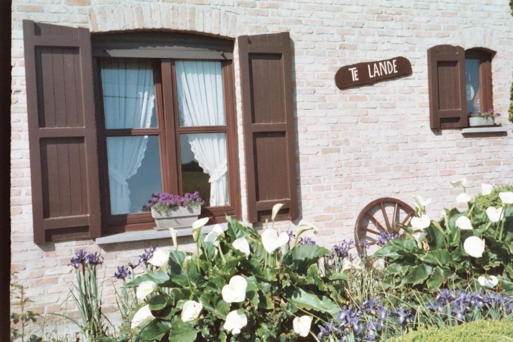 a brick building with windows and flowers in a garden at Vakantiehuis " Te Lande " in Torhout