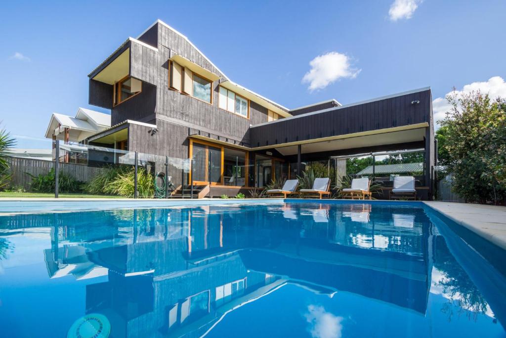 une maison avec une piscine en face de celle-ci dans l'établissement Byron Bay Accom Byron Beausoleil - Belongil Beach, à Byron Bay