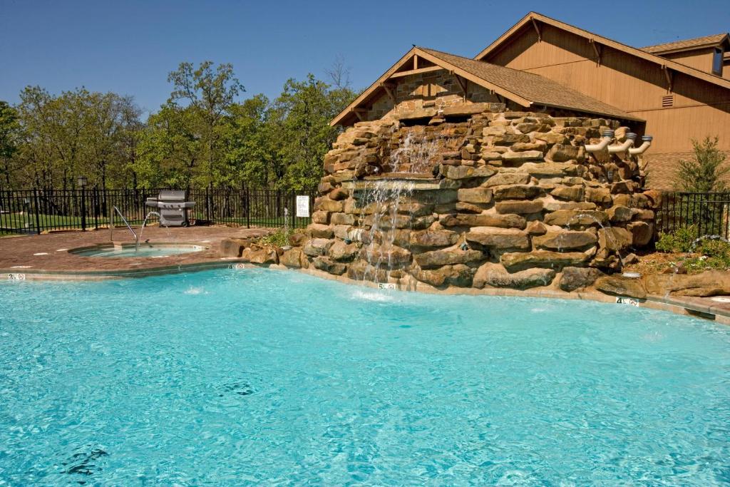 a swimming pool with a stone wall and a waterfall at POSTOAK Lodge and Retreat in Tulsa