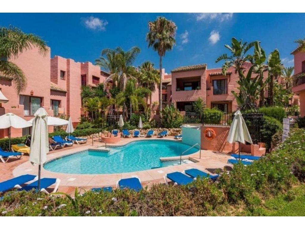 een zwembad met stoelen en parasols in een resort bij Estrelicia in Marbella