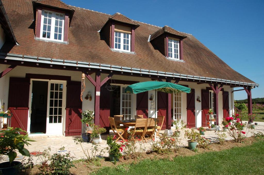 een huis met een tafel en stoelen en een paraplu bij Chambres d'Hôtes Les Coquelicots in Francueil