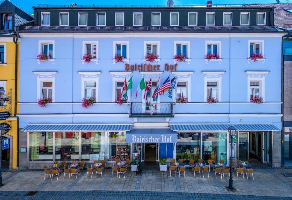 Hotel Bairischer Hof في ماركتردفيتس: مبنى ابيض امامه طاولات وكراسي