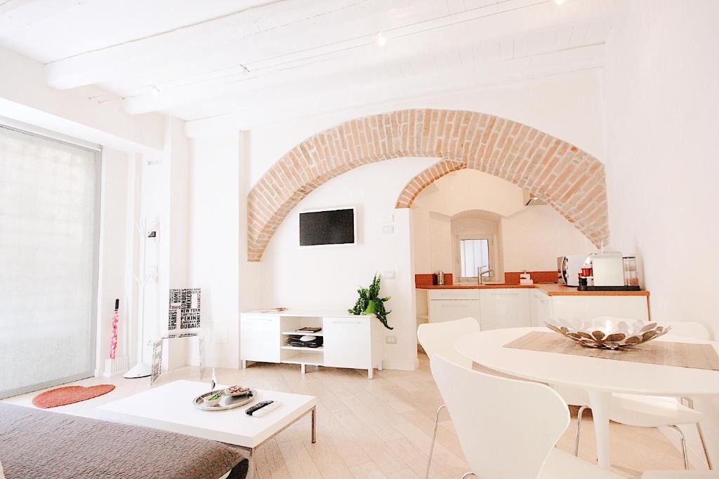 a white living room with a table and a kitchen at Le Nuove Cadreghe Apartments in Verona