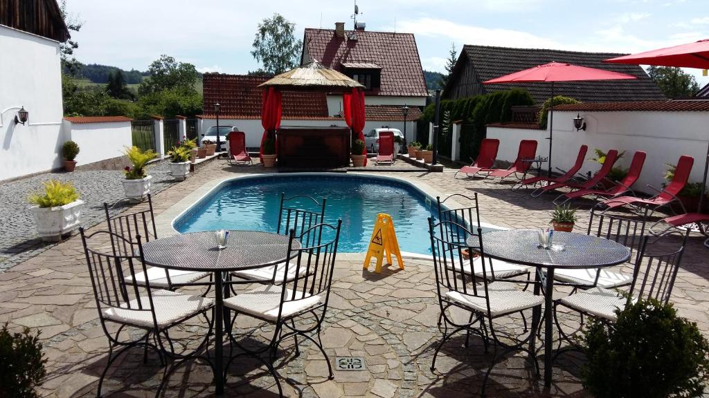 a pool with two tables and chairs next to a pool at Pension Šejko in Horní Planá