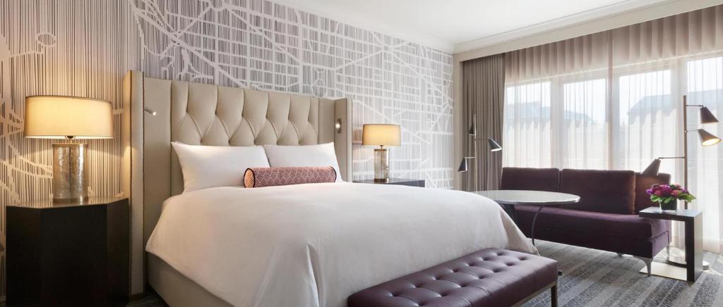 um quarto com uma grande cama branca e uma cadeira em Fairmont Washington DC Gold Experience em Washington