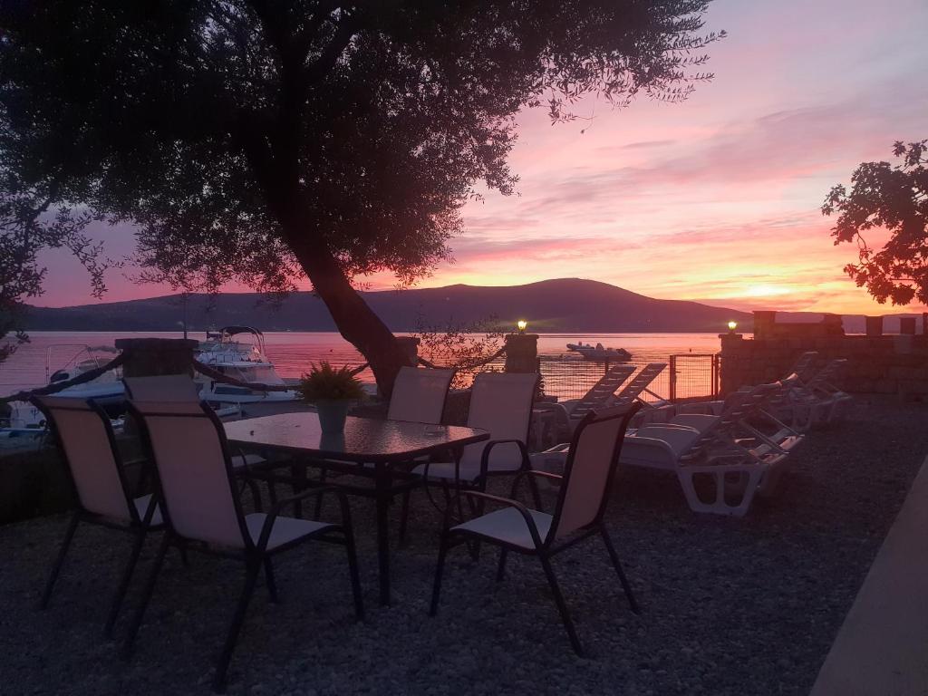 a table and chairs with a sunset in the background at Beach Apartments in Tivat