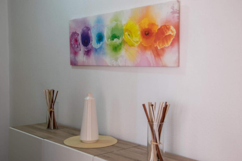 une peinture accrochée à un mur avec des vases sur une étagère dans l'établissement Apartamento Lince, à Matalascañas