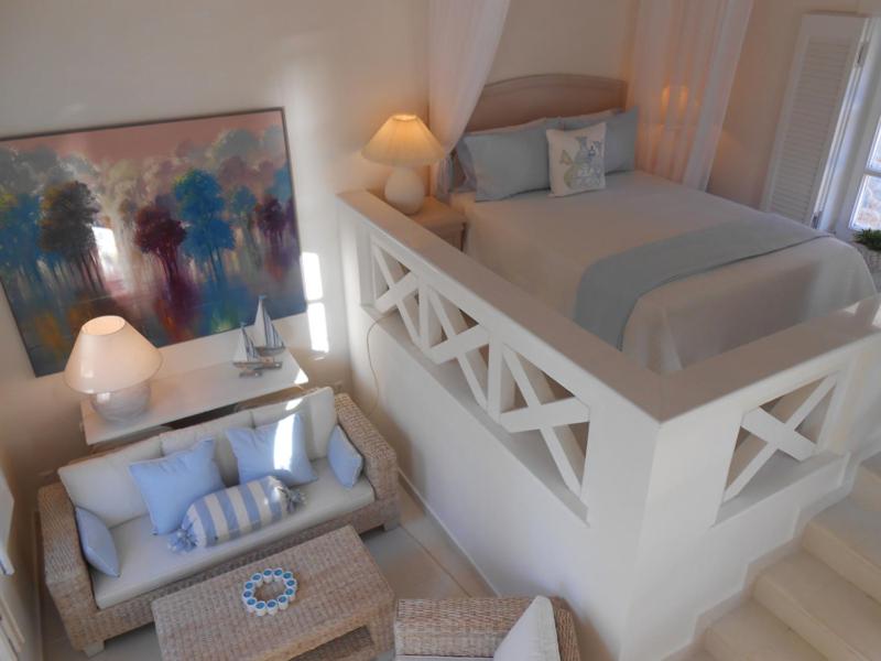 um quarto com uma grande cama branca e uma cadeira em HydraVista (Coral) em Hydra