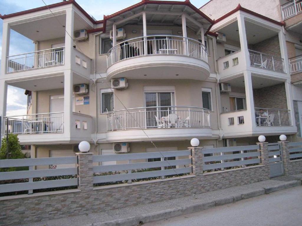 a large white building with balconies and a fence at Angie's Summertime in Nea Vrasna