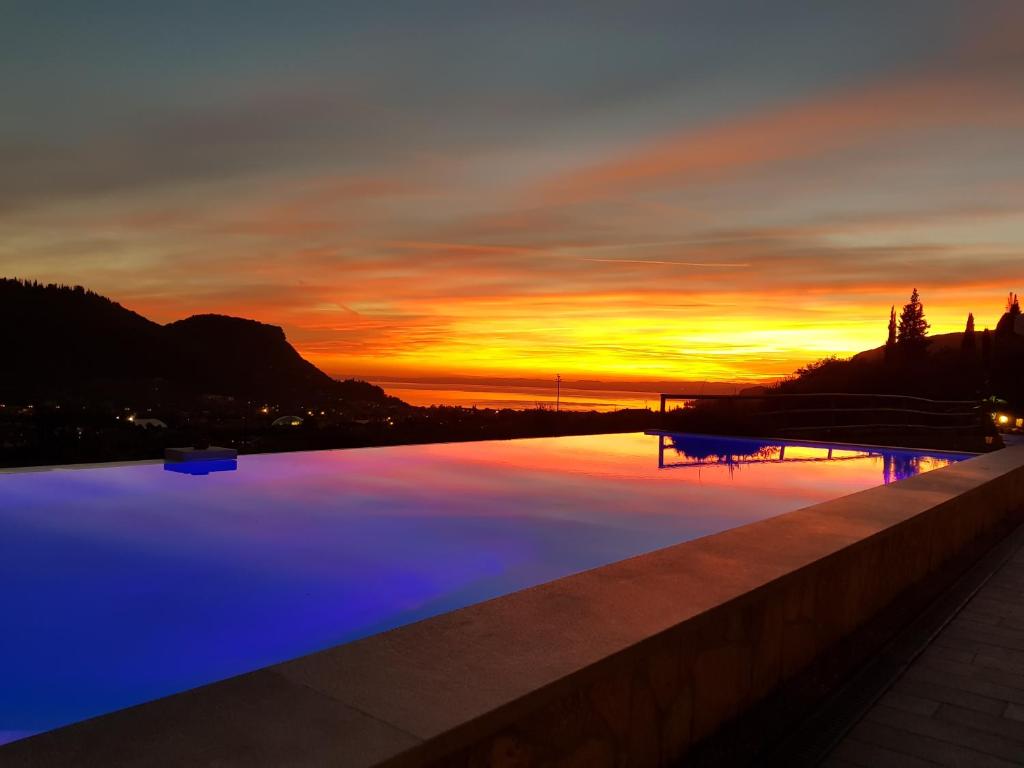 una piscina con puesta de sol en el fondo en Relais Villa Olivi, en Costermano