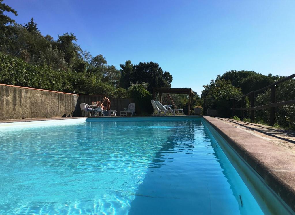 a swimming pool with blue water in a yard at Casa Bianca Villa pool with sea view, fenced garden, barbecue by ToscanaTour in Castellina Marittima