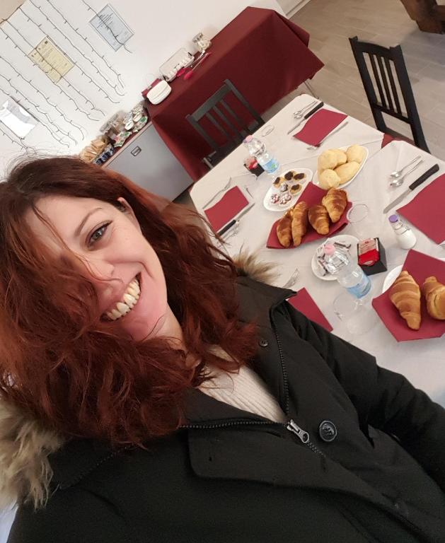 a woman with long red hair smiling at a table with food at Residenza Lisy Rooms Affittacamere in Verbania