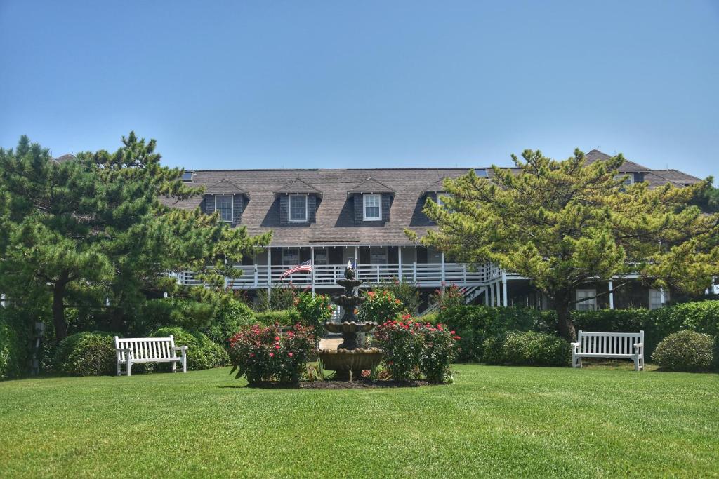 two benches in a park in front of a building at First Colony Inn in Nags Head