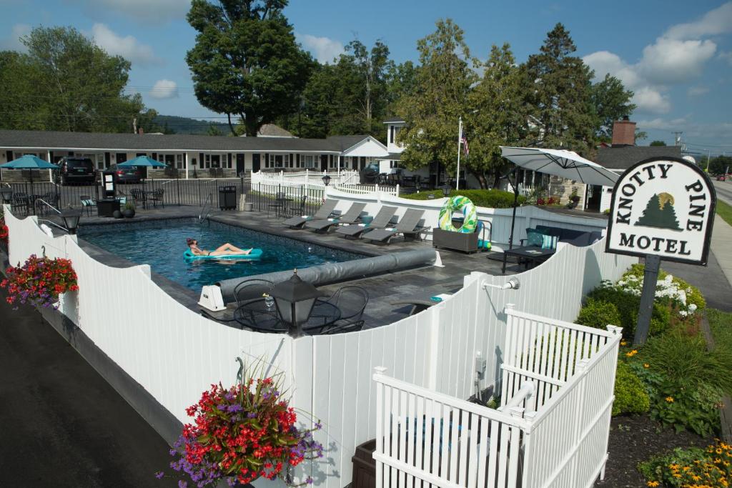 a pool at a motel with a person swimming in it at Knotty Pine Motel in Bennington