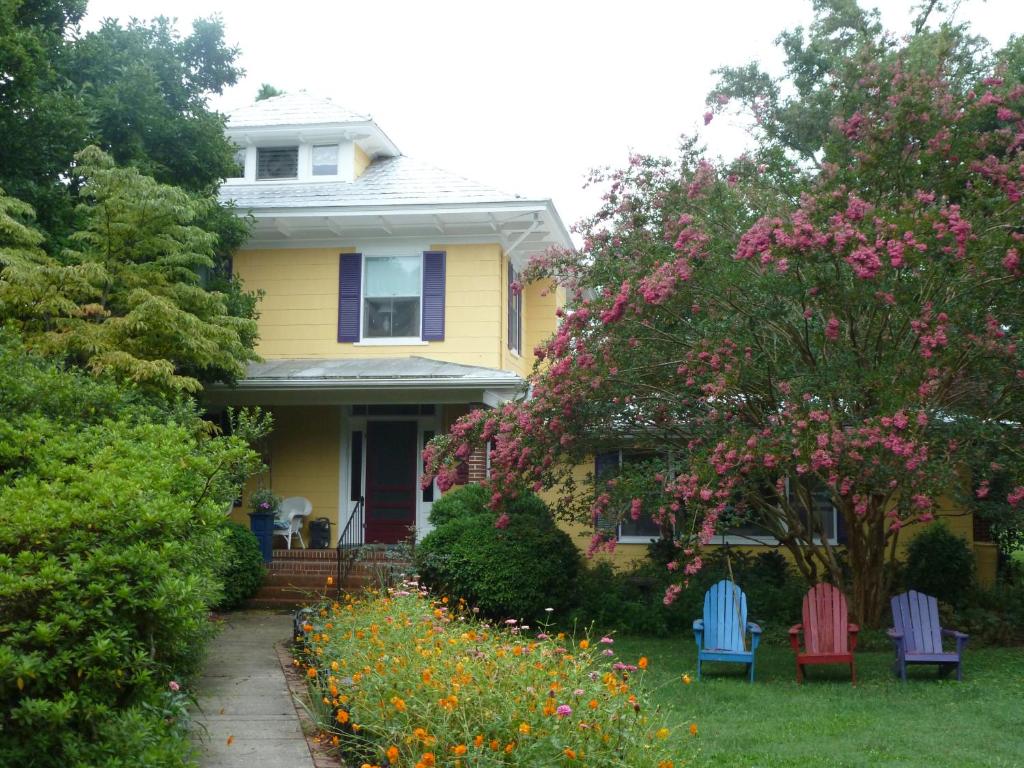 a yellow house with colorful chairs in the yard at Back INN Time B&B in Kilmarnock