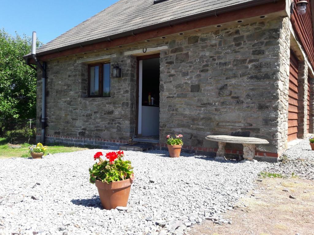 uma casa de pedra com dois potes de flores e um banco em The Barn Annexe, Cefn-Yr-Allt em Crickadarn
