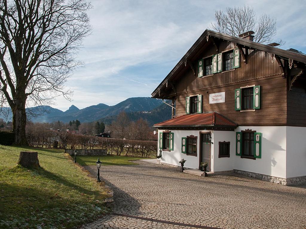 a large wooden house with green shutters on a road at Gästehaus Florian in Tegernsee