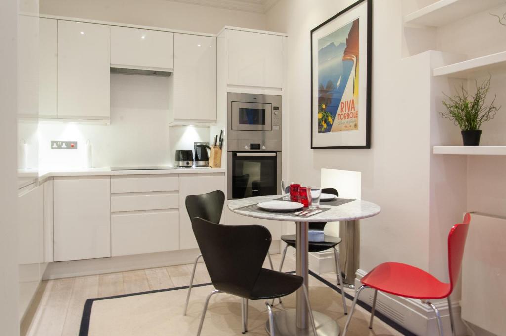a white kitchen with a small table and chairs at UNIQUE APARTMENT MARBLE ARCH in London