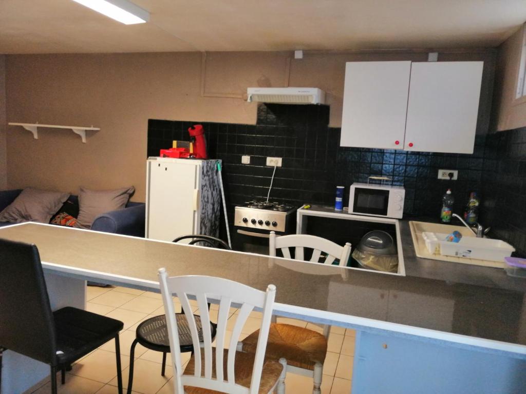 une cuisine avec des armoires blanches et un comptoir dans l'établissement Appartement proche du parc des expositions avignon, à Avignon