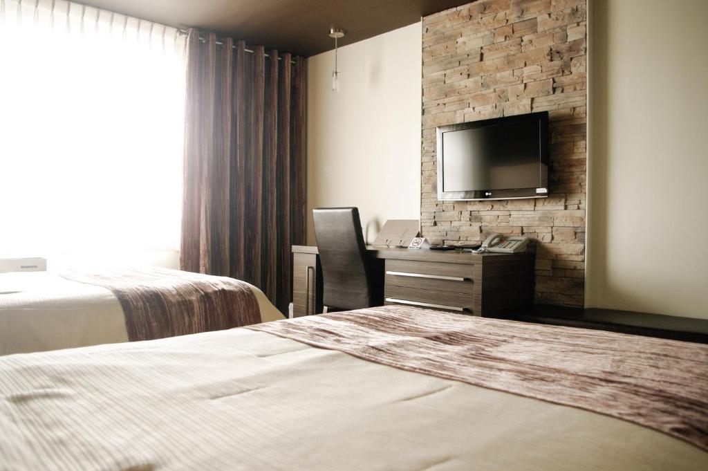 a hotel room with two beds and a flat screen tv at Complexe Hotelier Le 55 in Bécancour
