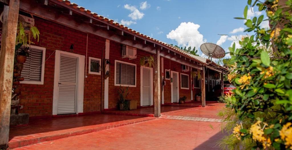 a red brick building with white shutters on it at Pousada Sucuri in Bonito