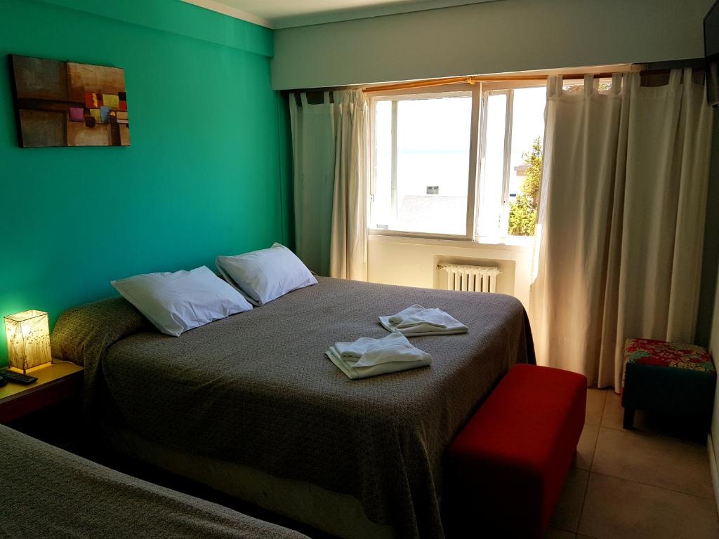 - une chambre avec un lit aux murs verts et une fenêtre dans l'établissement Hotel Flamingo, à San Carlos de Bariloche
