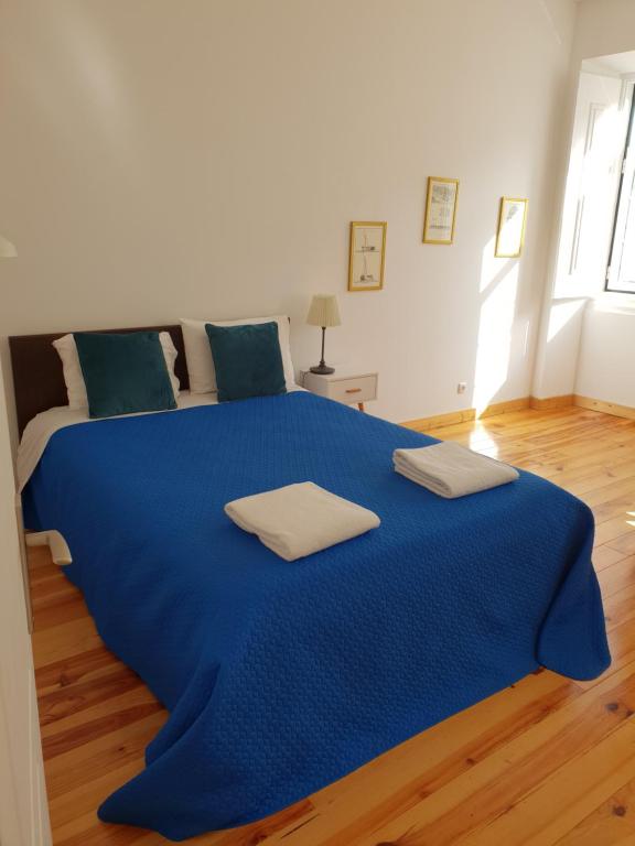 uma grande cama azul num quarto com pisos em madeira em Casa do Armador em Setúbal