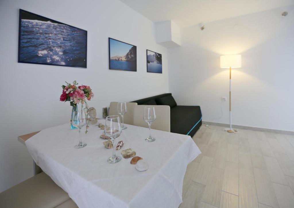 a white table with wine glasses and flowers on it at Tomas Art & Tomas Cave in Split