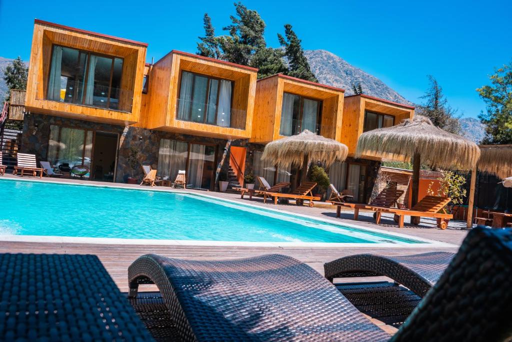 un complejo con una piscina con sillas y sombrillas en Cajón del Maipo Lodge, en San José de Maipo