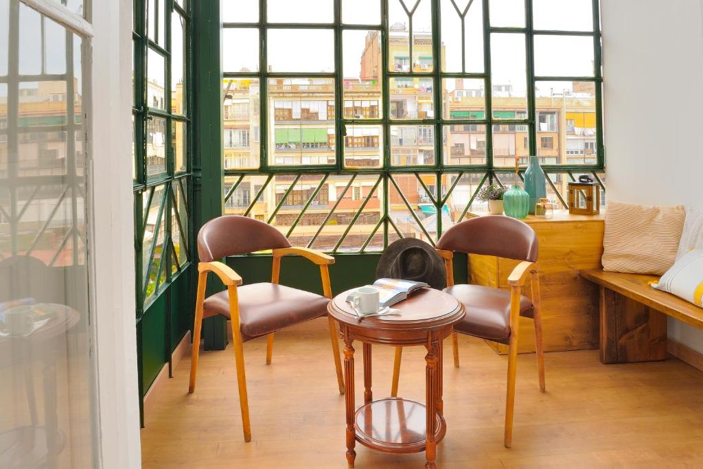 - une table et des chaises dans une chambre avec fenêtre dans l'établissement Hostal Girona, à Barcelone