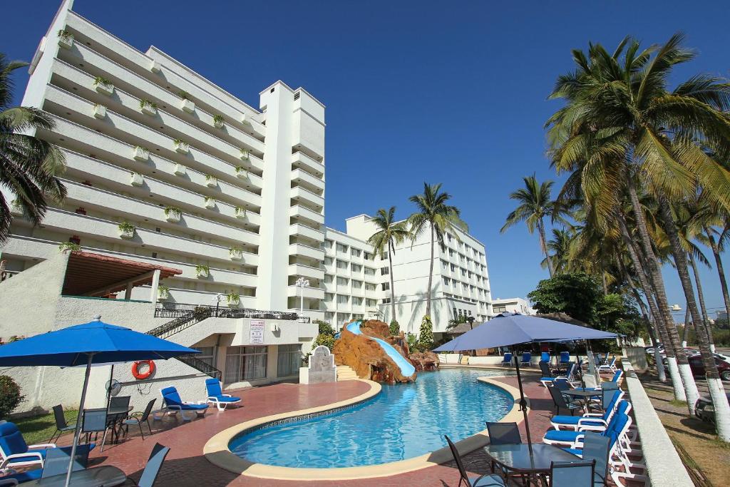 a hotel with a swimming pool with chairs and umbrellas at Don Pelayo Pacific Beach in Mazatlán