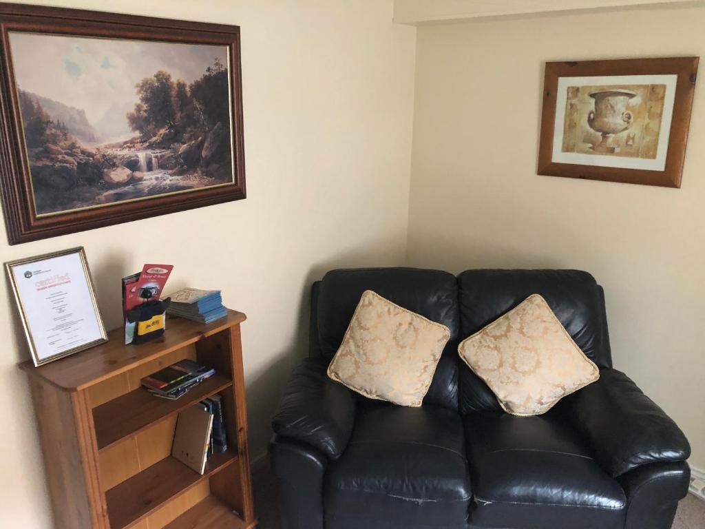 a black leather couch with two pillows in a room at bishop gate bnb in Derry Londonderry